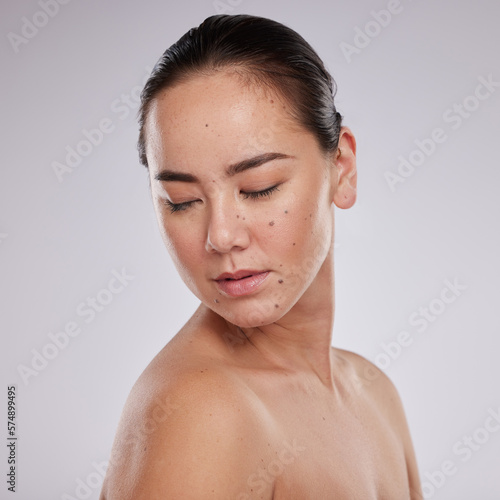 Skincare, beauty and woman in studio for cosmetics, dermatology and skin glow. Aesthetic asian model person with makeup, mole and luxury facial self care for health and wellness on grey background photo