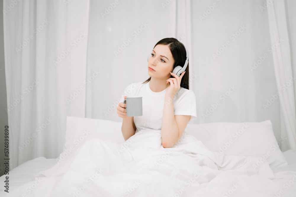 Beautiful young woman on a white bed with coffee cub and using smart phone at home. lifestyle concept. Beautiful young woman on a white bed with coffee cub and using smart phone at home. lifestyle concept.