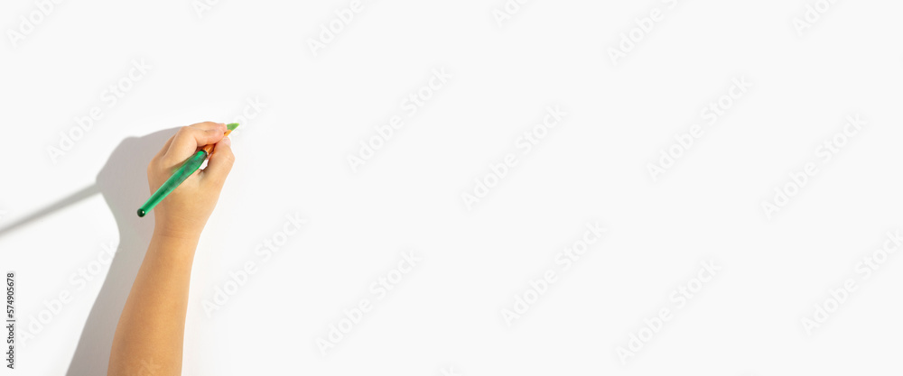 Left hand of the child holds a brush on a white background. Top view, flat lay. Banner Left hand of the child holds a brush on a white background. Top view, flat lay. Banner