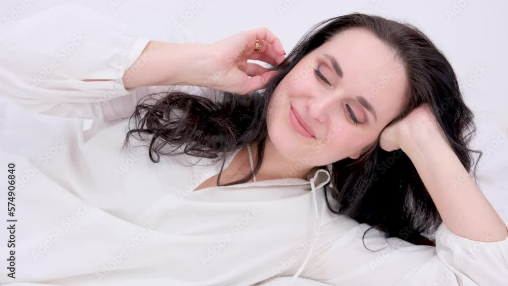 very beautiful middle-aged woman lying on the bed adjusting her hair white nightgown nightgown blue eyes black hair red nails manicure personal care Tenderness trying to lie down comfortably very beautiful middle-aged woman lying on the bed adjusting her hair white nightgown nightgown blue eyes black hair red nails manicure personal care Tenderness trying to lie down comfortably