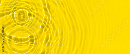 Drops fall on yellow water by sunlight. Top view, flat lay. Banner photo