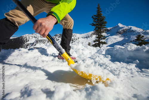 A climber shovels snow in order to make a flat spot to pitch his tent.