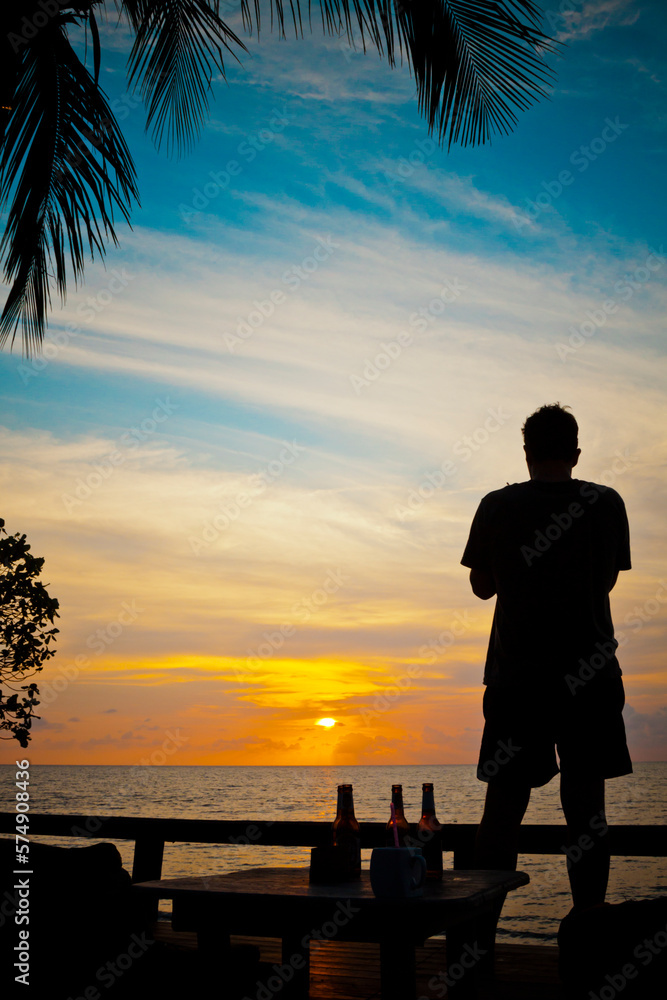 Silhouette Of A Man Watching The Sunset From A Beach On Koh Chang Island, Thailand Silhouette Of A Man Watching The Sunset From A Beach On Koh Chang Island, Thailand