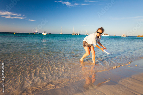 Woman throwing plastic disc on beach,Â RottnestÂ Island, Perth, Western Australia, Australia photo