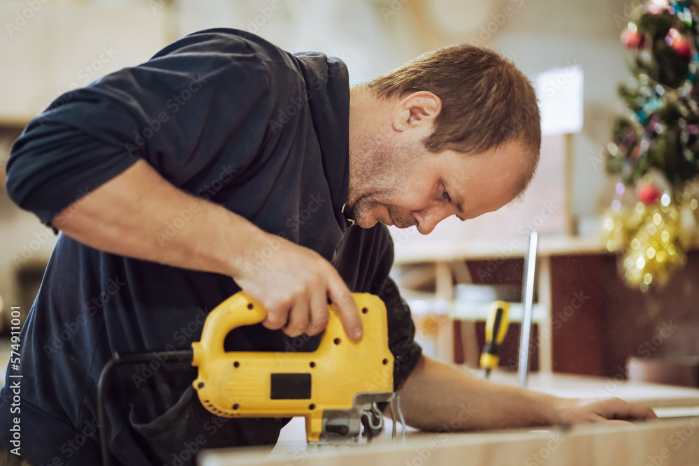 Carpenter working with an electric jigsaw, sawing wood board with a saw. Carpenter working with an electric jigsaw, sawing wood board with a saw.