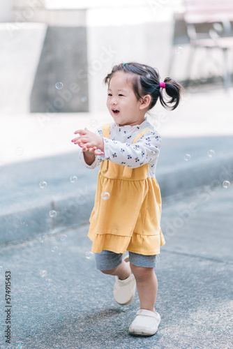 A cute happy little girl asian playing bubble outdoor.