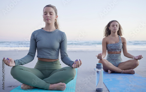 Yoga, meditation and wellness with woman friends on the beach for fitness, mental health or zen. Training, exercise or chakra with female and personal trainer meditating legs crossed on the sand