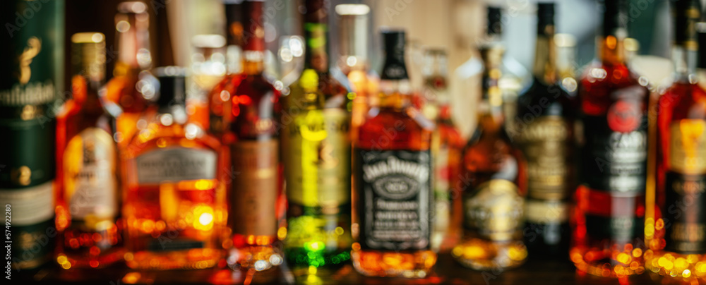 Beautiful bokeh from a row of alcoholic bottles in backlight. - obrazy, fototapety, plakaty 