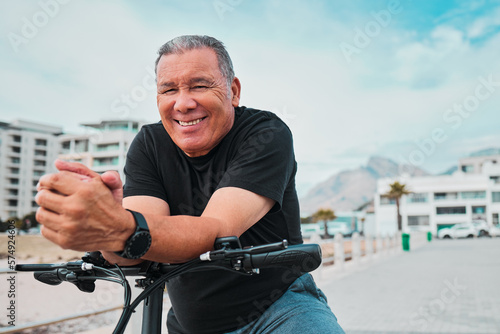 Portrait, bike and cycling with a senior man on the promenade, riding eco friendly transport for travel. Face, smile and health with a happy mature male cyclist sitting on his bicycle outdoor