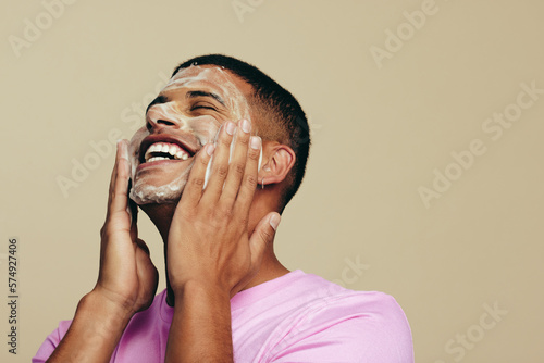 Schilderij op canvas Starting his skincare routine with a refreshing face wash, man applies a facial