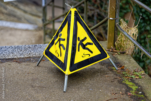 Yellow mobile triangle warning sign slippery floor at footpath at famous Rhine Falls on a foggy winter day. Photo taken February 16th, 2023, Laufen Uhwiesen, Switzerland. photo