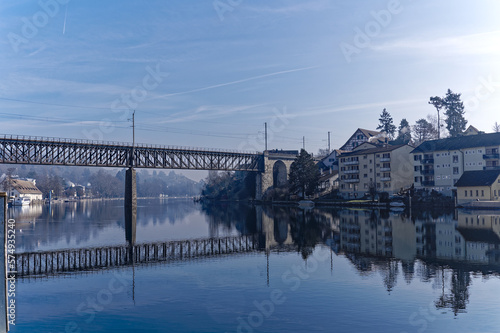 Scenic view of Rhine River at City of Schaffhausen with railway bridge and village of Feuerthalen in the background on a sunny winter day. Photo taken February 16th, 2023, Schaffhausen, Switzerland.