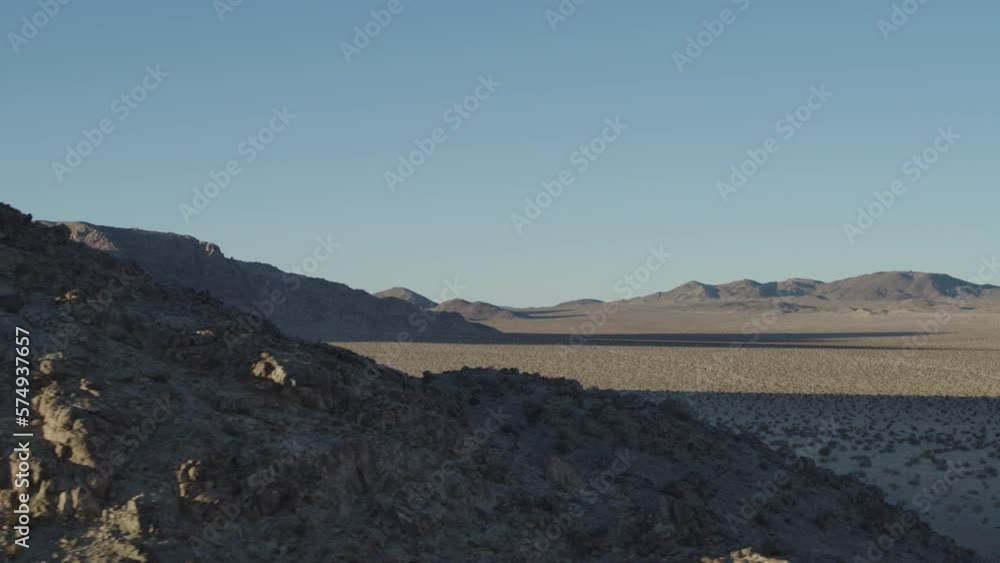 Aerial revealing from cliffs to dry lakebed in Johnson Valley, California at sunset