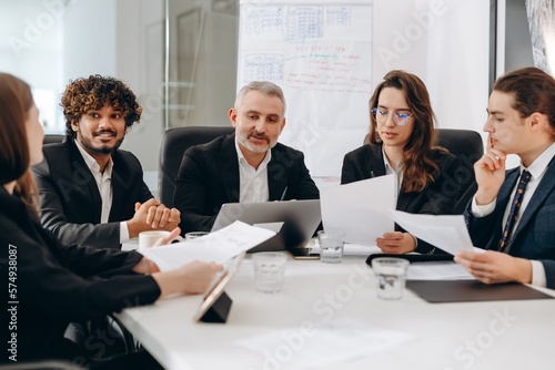 Group of businesspeople reading business report. Office managers doing paperwork during conference. Confident executive having meeting with his employees