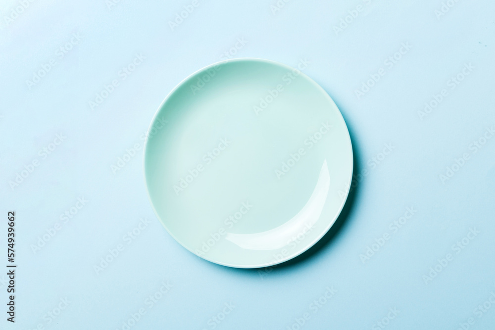 Obraz premium Top view of isolated of colored background empty round blue plate for food. Empty dish with space for your design