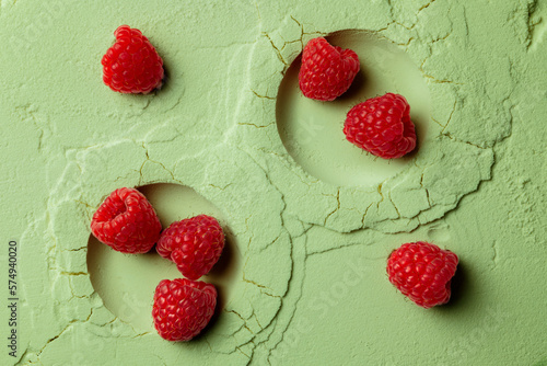 Raspberries on a green decorative background. Ripe berry on light green powdered background.