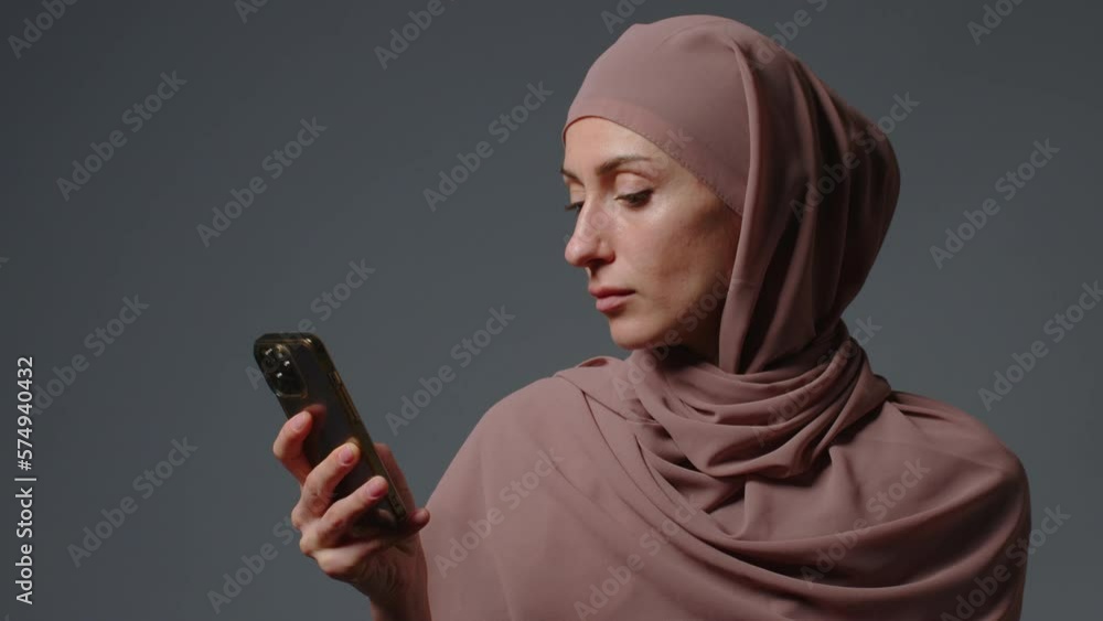 Portrait of happy muslim business woman enjoy success on mobile phone outdoors. Closeup joyful islamic girl reading good news on cellphone. Surprised ethnic lady in hijab celebrating victory Portrait of happy muslim business woman enjoy success on mobile phone outdoors. Closeup joyful islamic girl reading good news on cellphone. Surprised ethnic lady in hijab celebrating victory