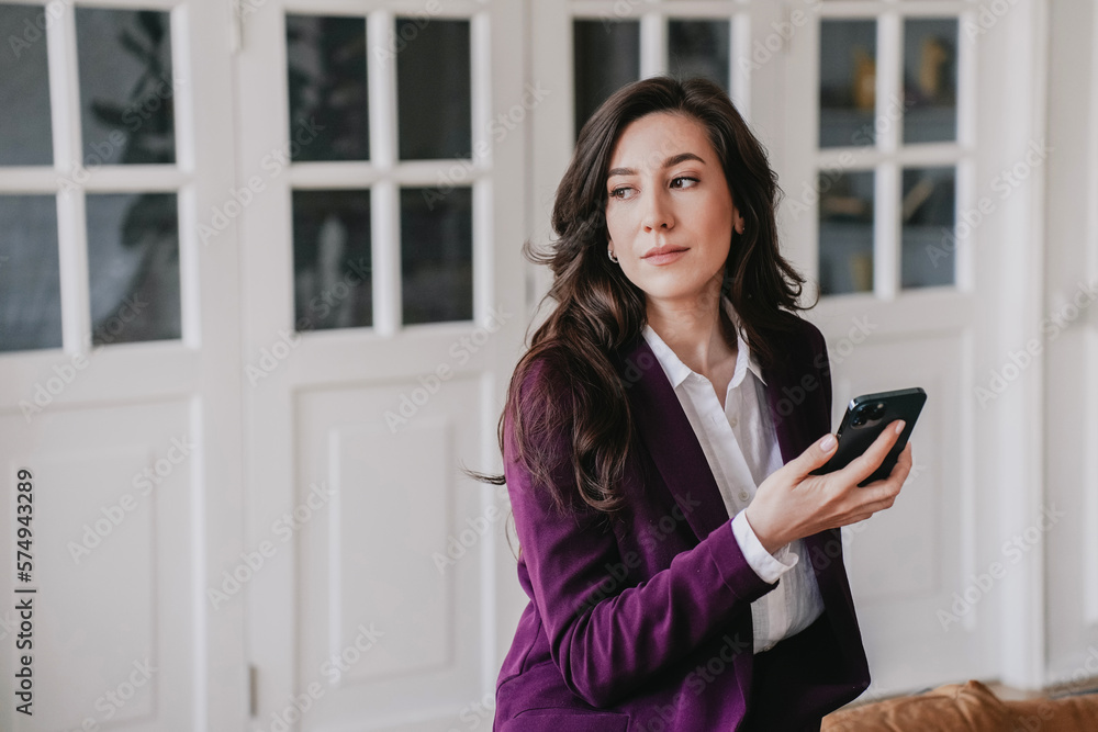 Exhausted brunette European businesswoman in violet suit sitting on leather couch holds phone looks aside with pensive face tired at home. Puzzled Hispanic woman feels fatigue. Failure, mistake. Exhausted brunette European businesswoman in violet suit sitting on leather couch holds phone looks aside with pensive face tired at home. Puzzled Hispanic woman feels fatigue. Failure, mistake.
