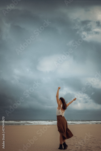 A beautiful young woman walks towards the stormy sea