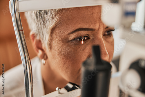 Laser, vision or senior customer in eye exam for eyesight at optometrist office in assessment or consultation. Face of mature woman testing or checking vision to help iris or retina visual health photo