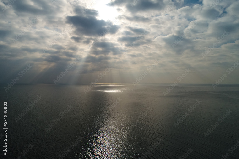 Sun rays bursting through cumulus clouds over the sea. Aerial sea landscape in a spectacular cloudy day.