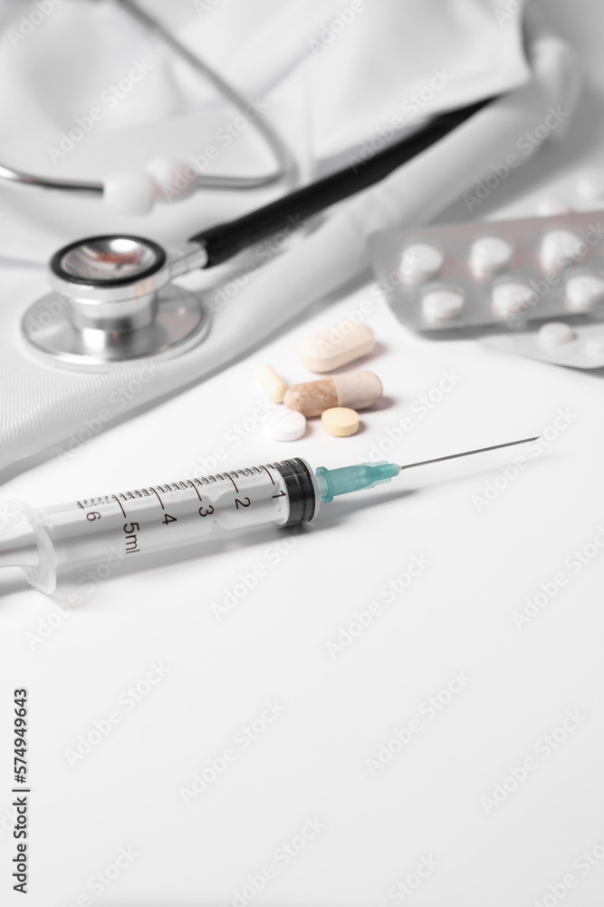 stethoscope, pills and syringe on a doctor's gown stethoscope, pills and syringe on a doctor's gown