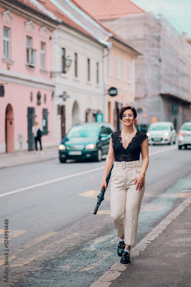 Woman wearing beige pants and a black lace top walking in the city street