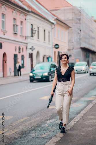Woman wearing beige pants and a black lace top walking in the city street © Zamrznuti tonovi