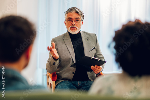 Senior man psychiatrist talking with his patients during therapy session photo