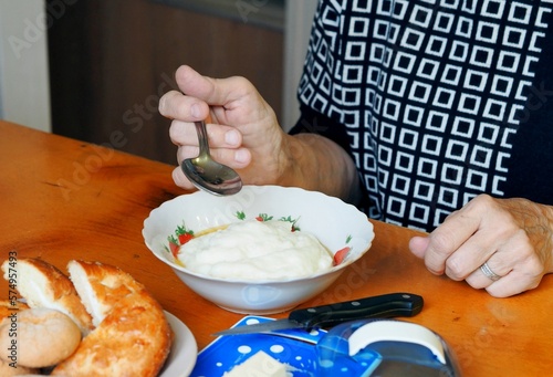 An elderly woman has milk porridge with butter for breakfast. Natural healthy food for seniors