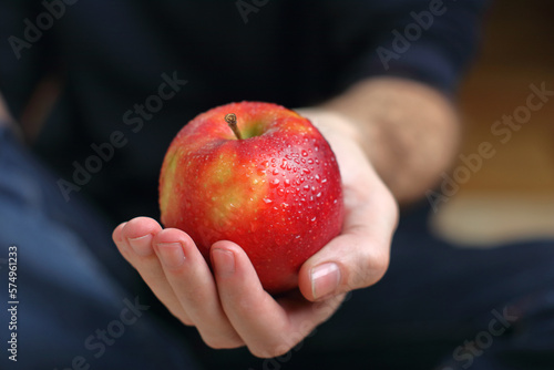 a person holds a red apple in his hand in drops
