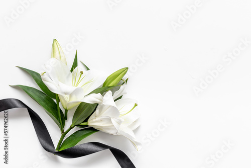 Two white liles flowers with black ribbon. Mourning or funeral background photo