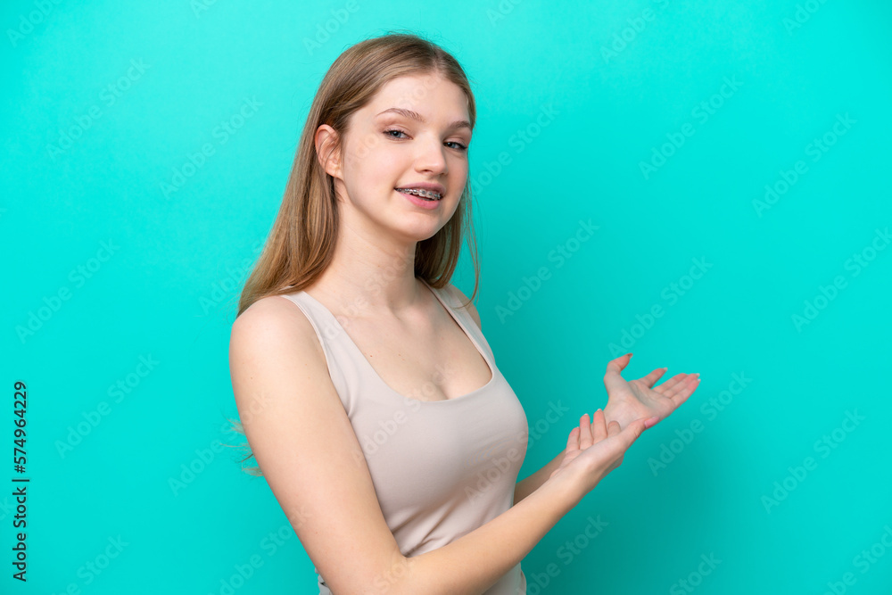 Teenager Russian girl isolated on blue background extending hands to the side for inviting to come Teenager Russian girl isolated on blue background extending hands to the side for inviting to come