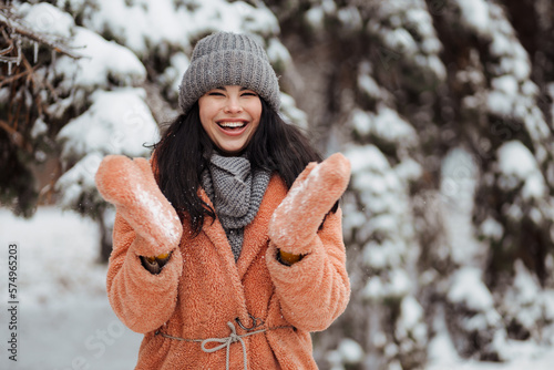 Pretty young long-haired woman in pink coat enjoy winter day at snowy park