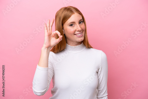 Young redhead woman isolated on pink background showing ok sign with fingers