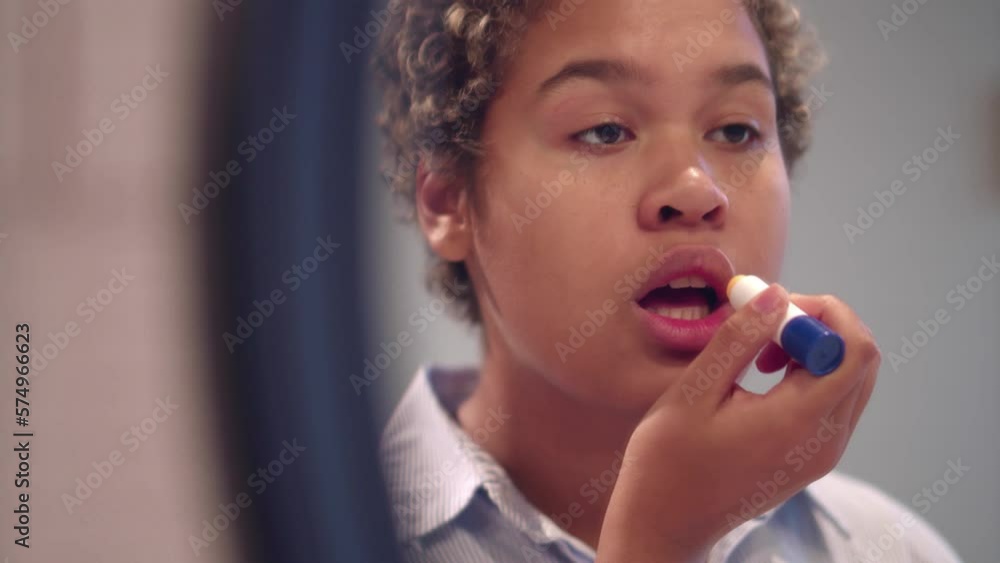 Beautiful young African-American woman applying lipstick looking in mirror. Realtime Beautiful young African-American woman applying lipstick looking in mirror. Realtime