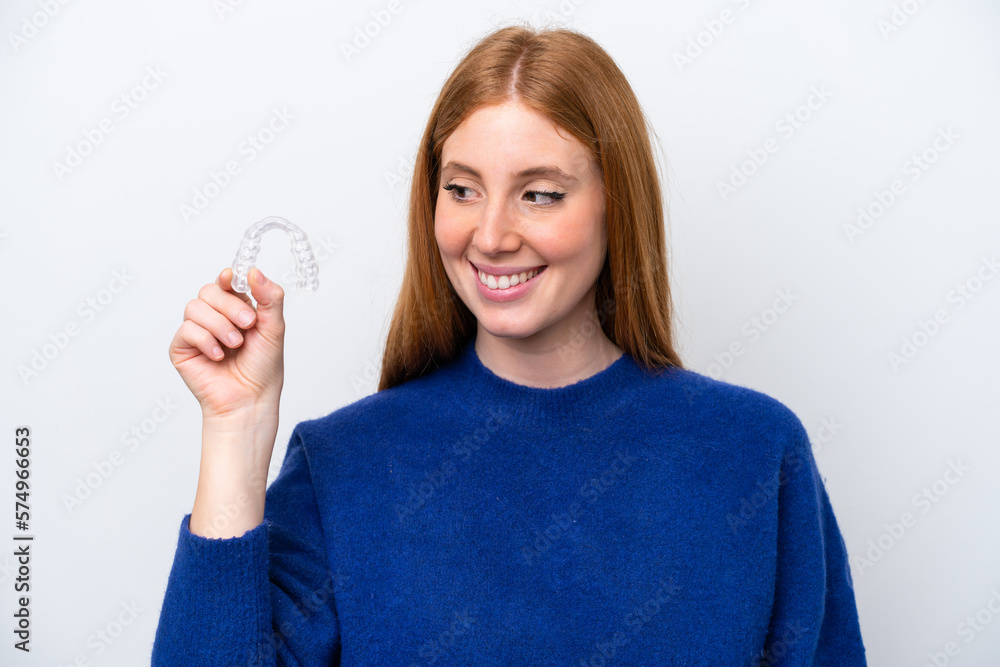 Young redhead woman holding invisible braces isolated on white background with happy expression Young redhead woman holding invisible braces isolated on white background with happy expression