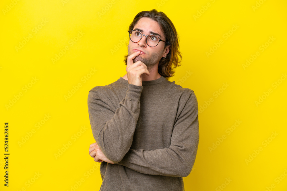 Caucasian handsome man isolated on yellow background having doubts and thinking Caucasian handsome man isolated on yellow background having doubts and thinking