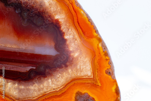 White, dark and light orange and red semi-transparent agate slice crystal, banded chalcedony stone isolated on a white background surface with detail. Abstract crystal image with lots of copy space