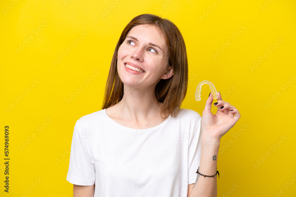 Young English woman holding invisible braces thinking an idea while looking up Young English woman holding invisible braces thinking an idea while looking up