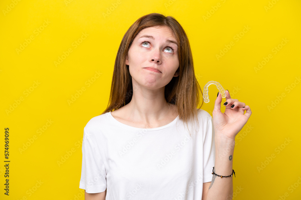 Young English woman holding invisible braces and looking up Young English woman holding invisible braces and looking up