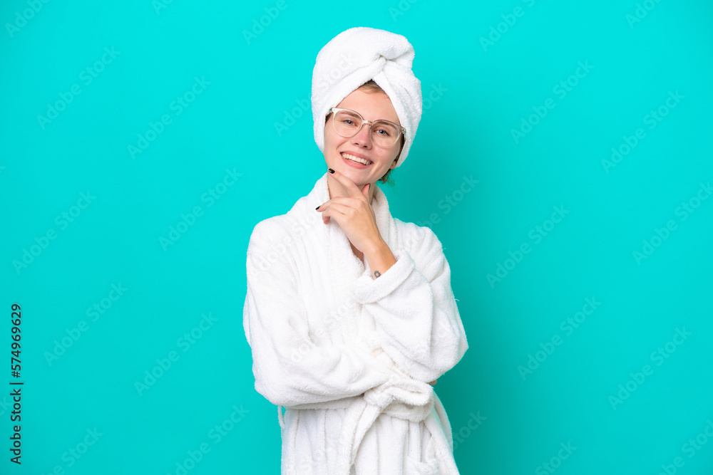 Young woman in a bathrobe isolated on blue background with glasses and smiling Young woman in a bathrobe isolated on blue background with glasses and smiling