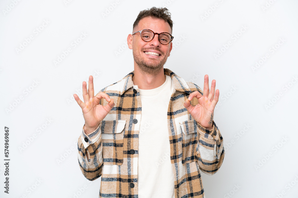 Young caucasian handsome man isolated on white background showing ok sign with two hands Young caucasian handsome man isolated on white background showing ok sign with two hands