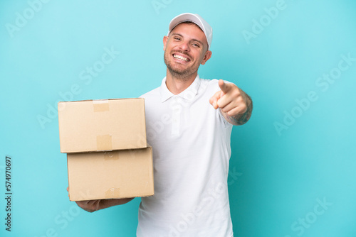 Delivery caucasian man isolated on blue background pointing front with happy expression © luismolinero