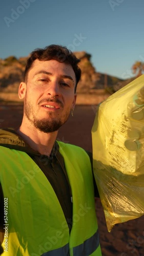 Influencer making a video with his cell phone for social networks showing the trash he has collected from the beach to his followers. Vertical video. Influencers with the environment concept
