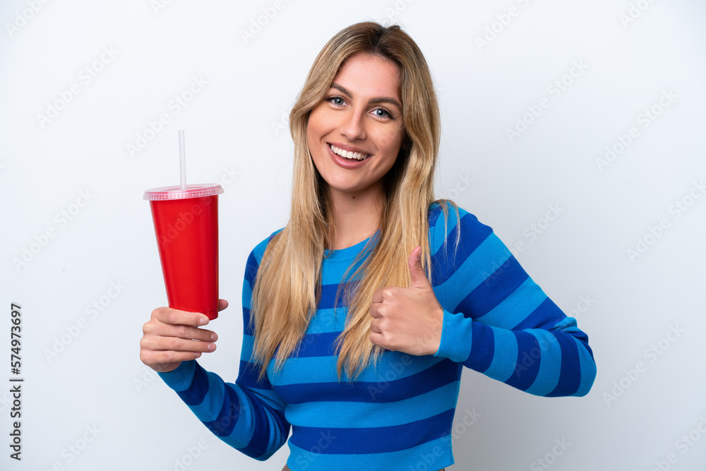 Young Uruguayan woman drinking soda isolated on white background giving a thumbs up gesture Young Uruguayan woman drinking soda isolated on white background giving a thumbs up gesture