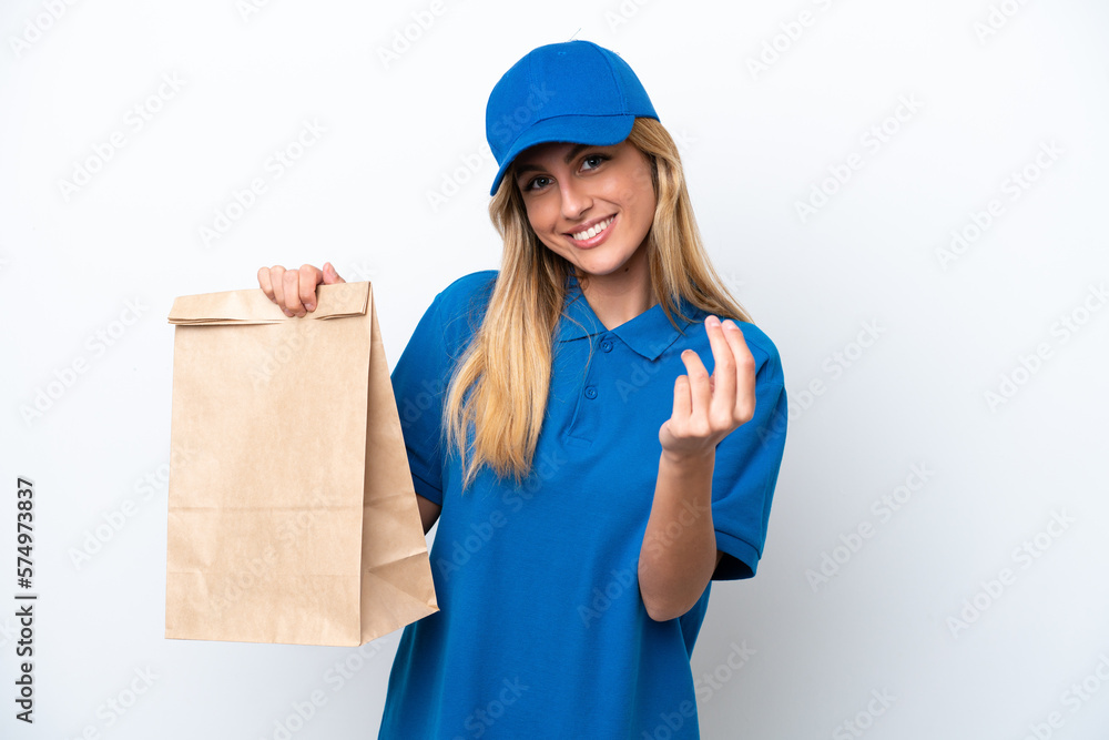 Young Uruguayan woman taking a bag of takeaway food isolated on white background making money gesture Young Uruguayan woman taking a bag of takeaway food isolated on white background making money gesture