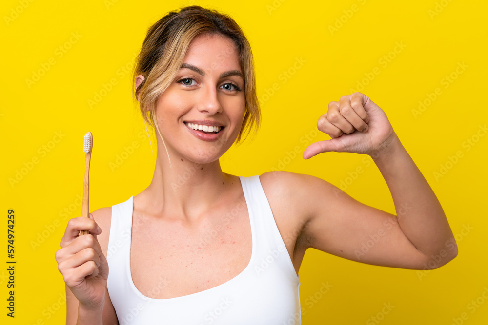 Young Uruguayan woman brushing teeth isolated on yellow background proud and self-satisfied Young Uruguayan woman brushing teeth isolated on yellow background proud and self-satisfied