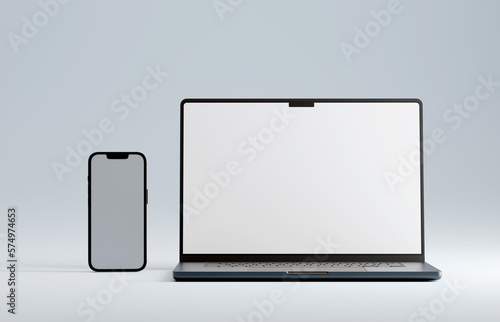 Gunmetal or space grey colored laptop and smartphone on blue studio background. Empty white mockup screen.