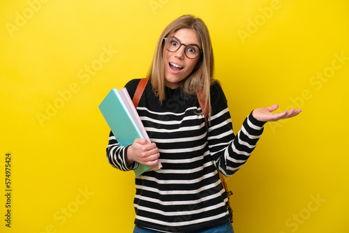 Young student woman isolated on yellow background background with shocked facial expression